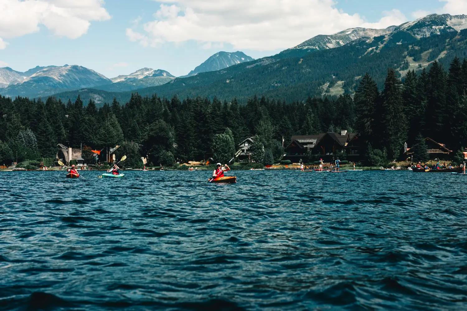 Kayakers on blue water beneath mountain ridges