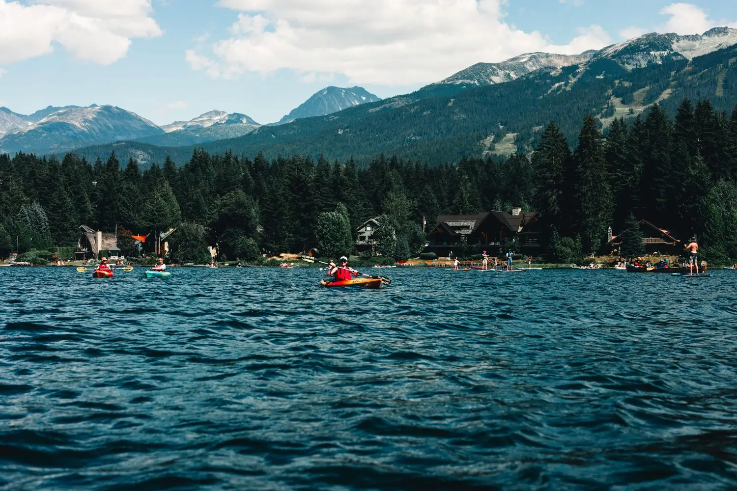 Kayakers crossing a forested mountain lake