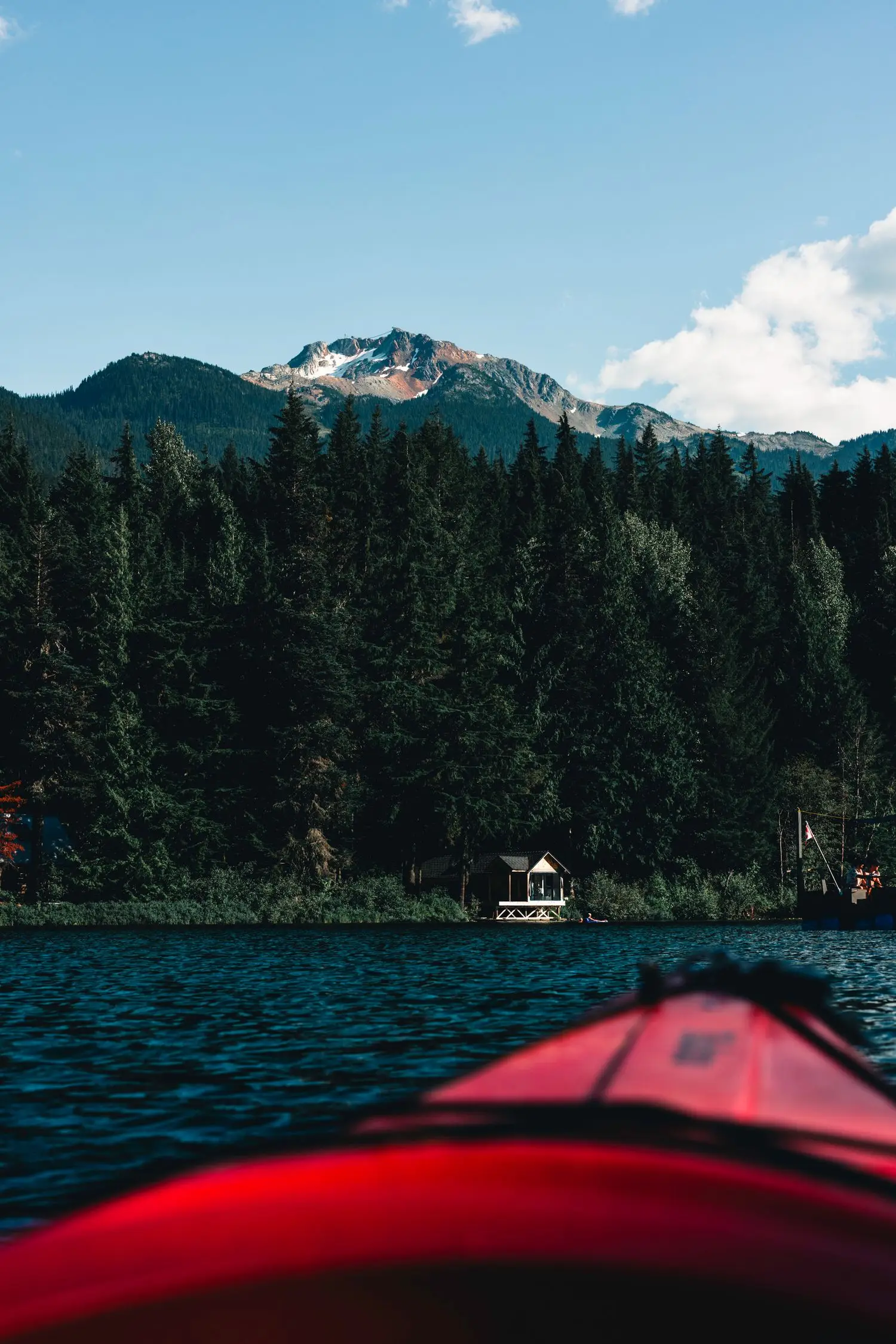 View from a red kayak toward a forested shore