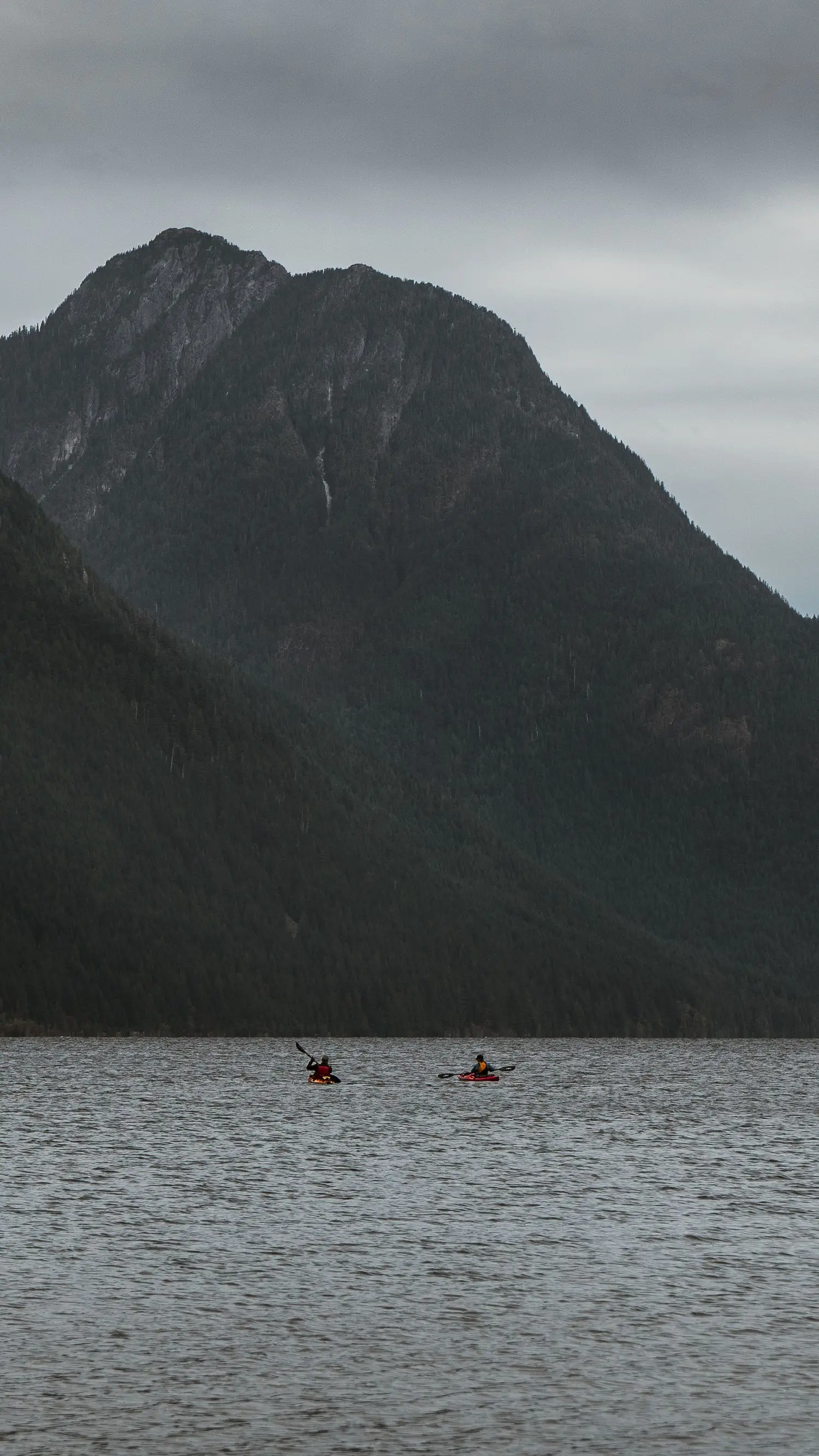 Kayakers crossing dark mountain water
