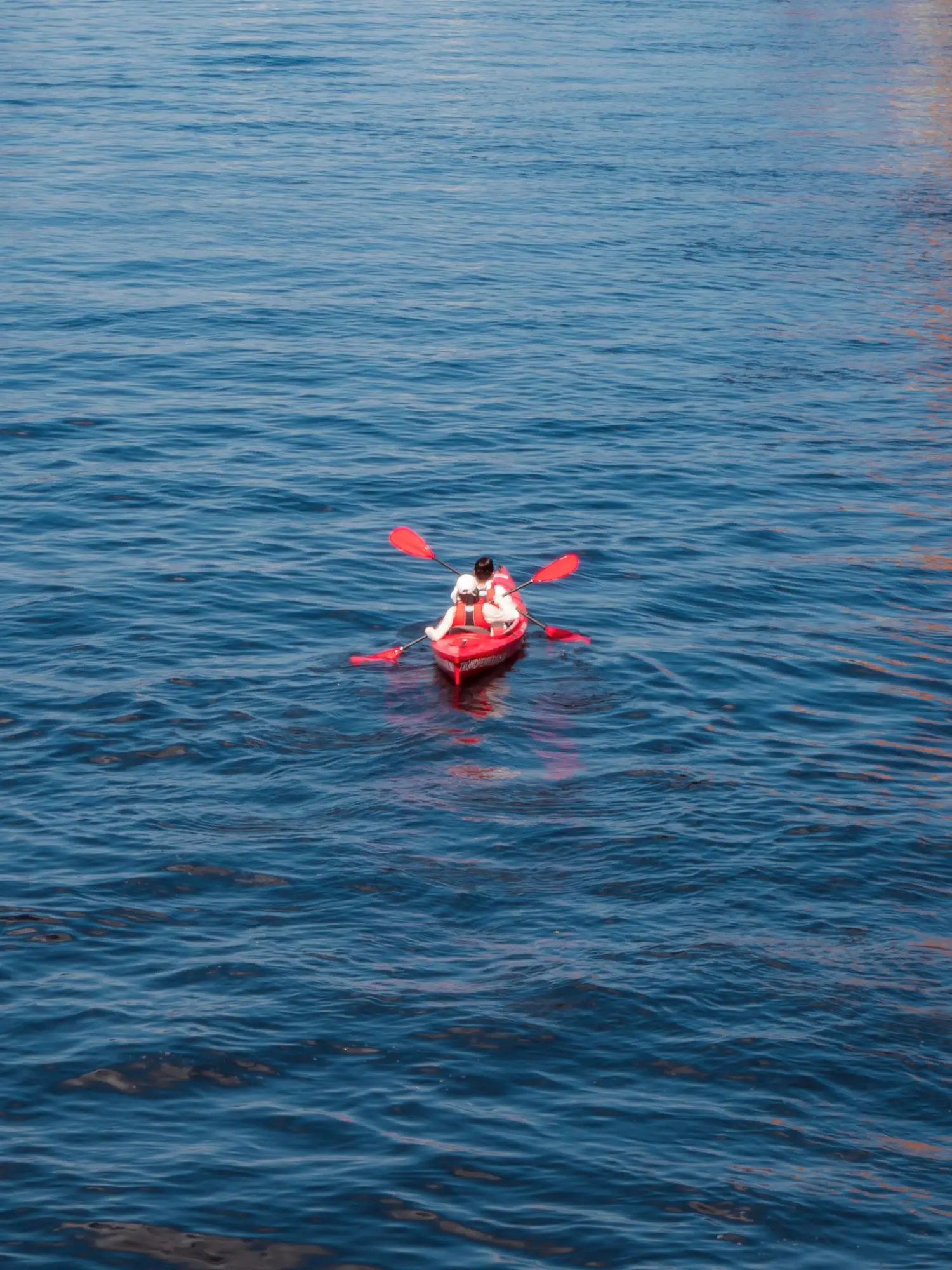 Small red kayak on open blue water