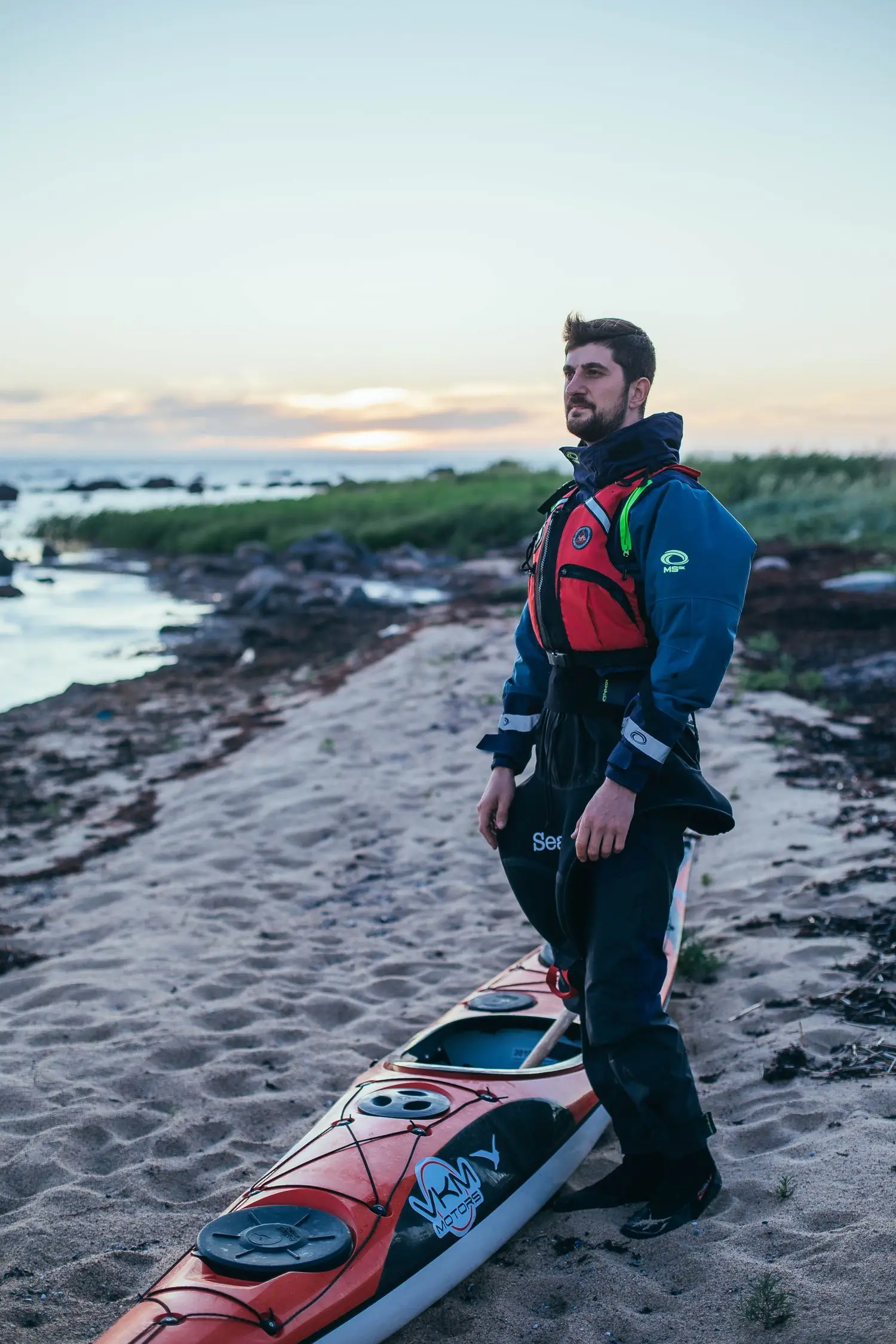 Kayaker in paddling gear standing beside the shoreline